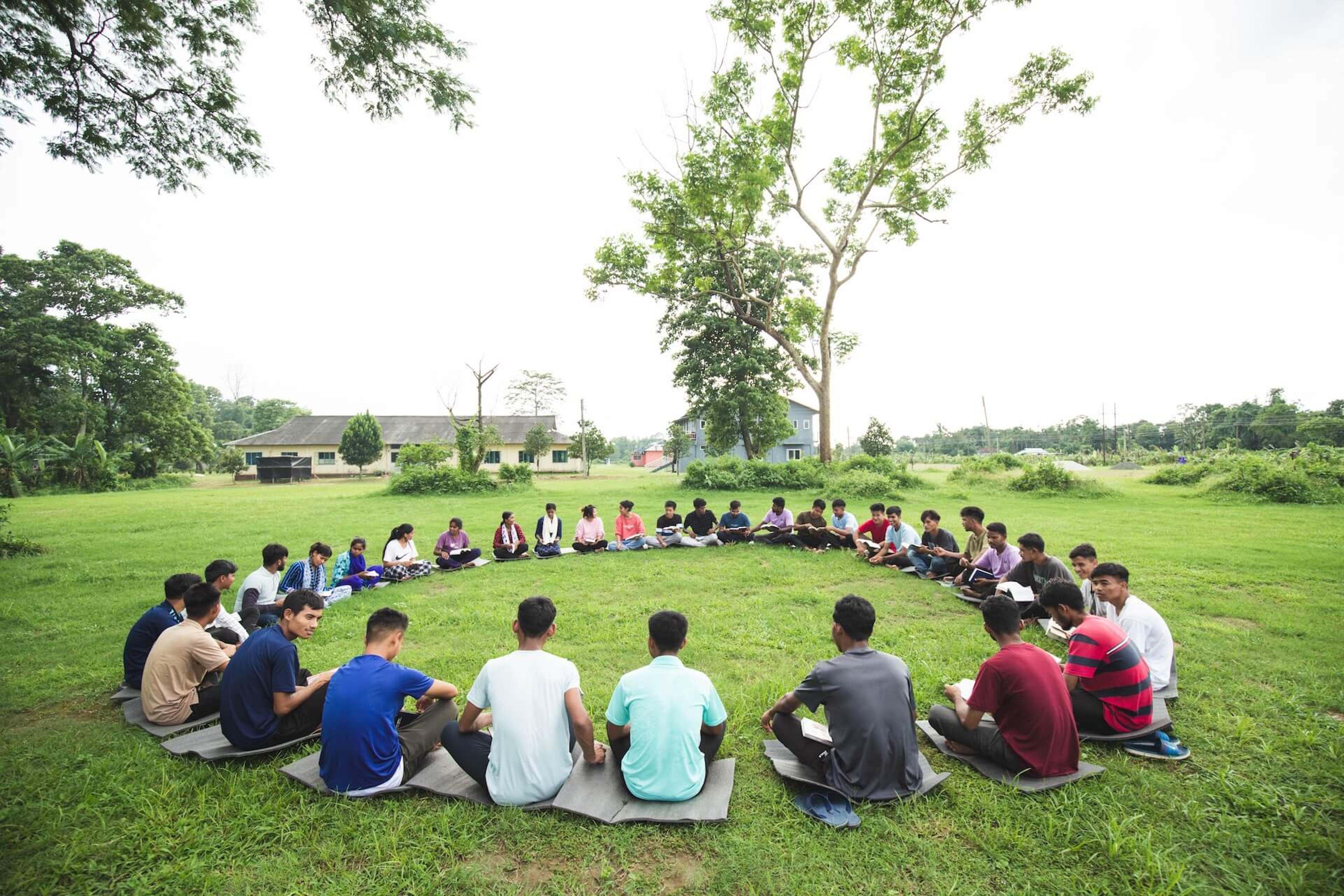 A group of students sitting in a circle on a lawn