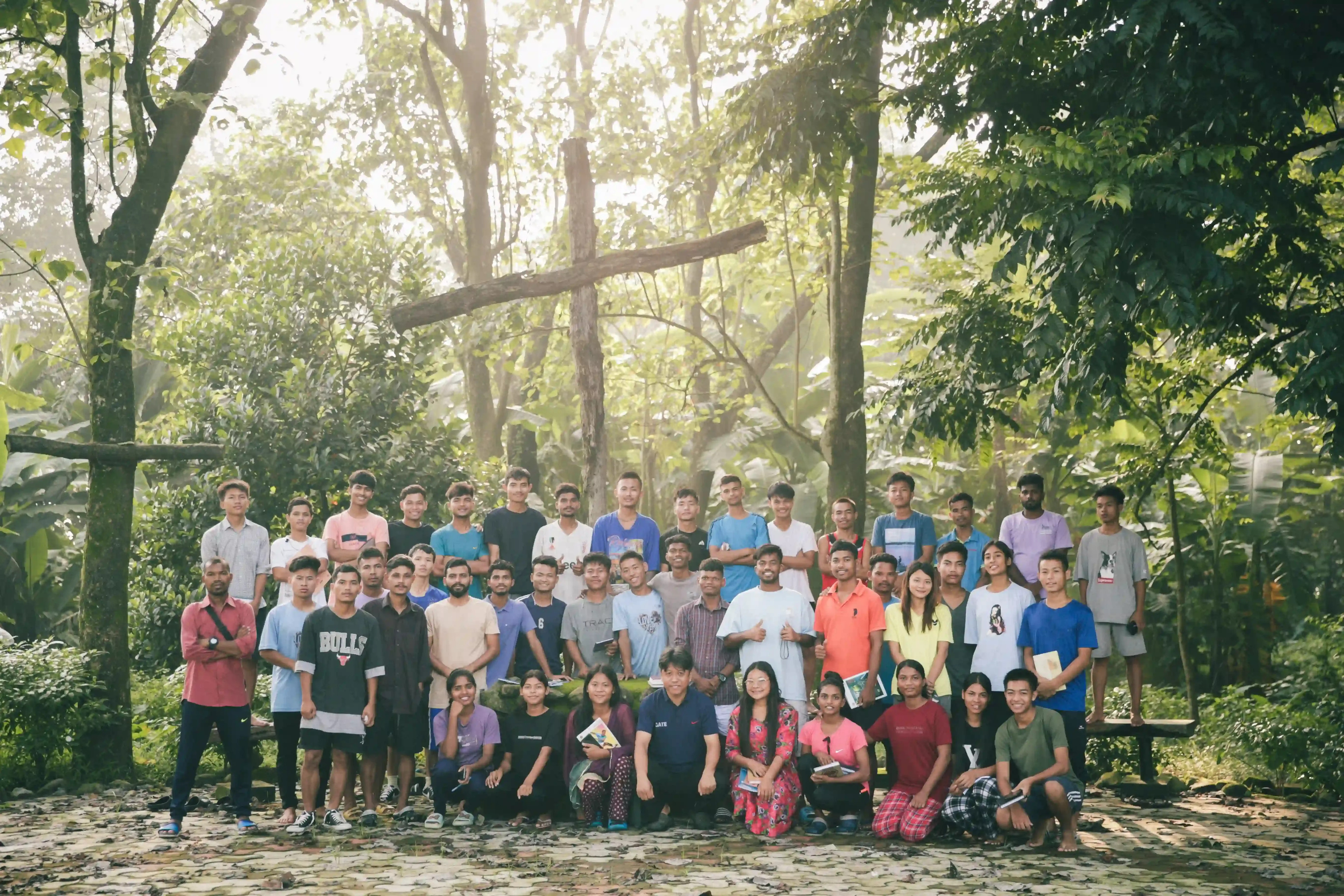 Students standing in front of a wooden cross in a jungle